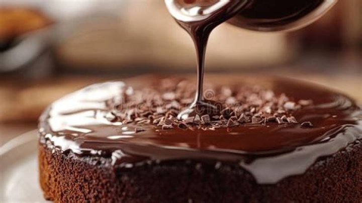 Ganache being poured over a pan of coconut brownies.